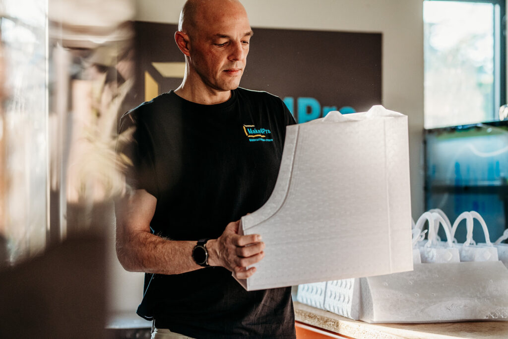 Stijn Moris met een groot wit 3D-geprint onderdeel in het atelier van Make4PRO